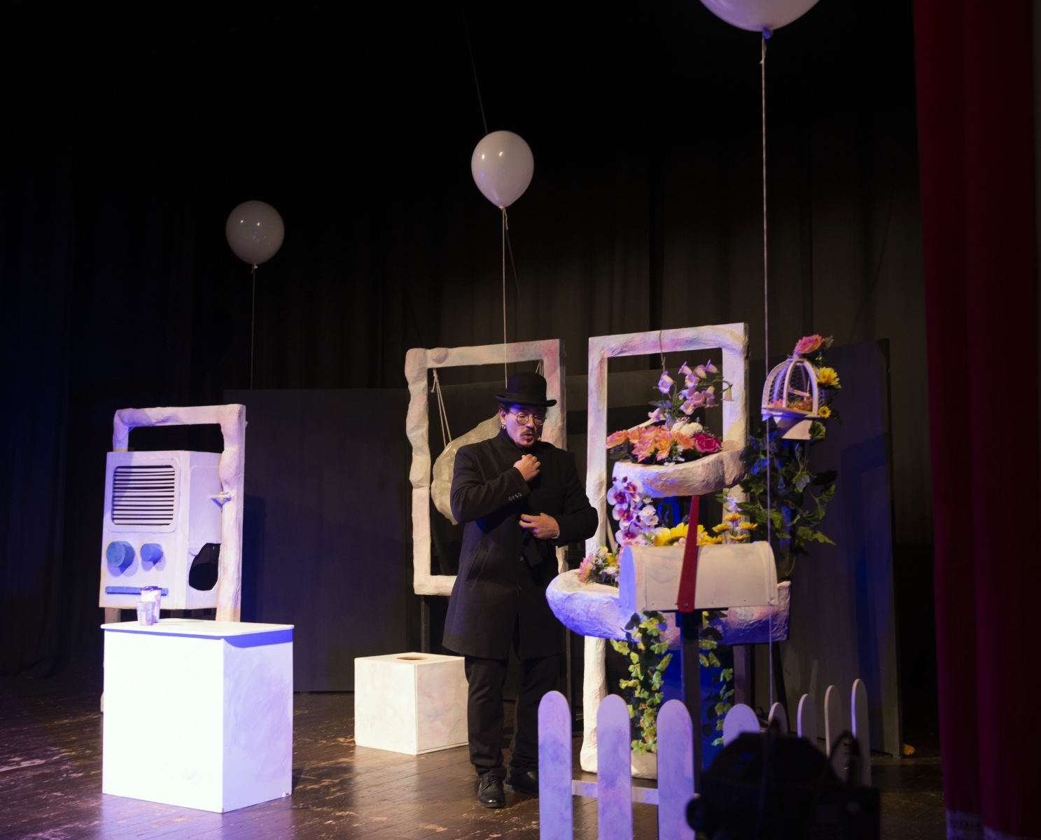 Attore sul palco con palloni e scenografia fiorita